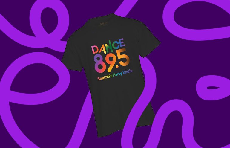 A black T-shirt with the colorful text "DANCE 89.5 Seattle's Party Radio" displayed on the front. The background features bold purple and magenta swirling patterns.