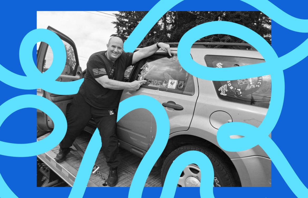 A man pointing at stickers on a car that is up on a lift.