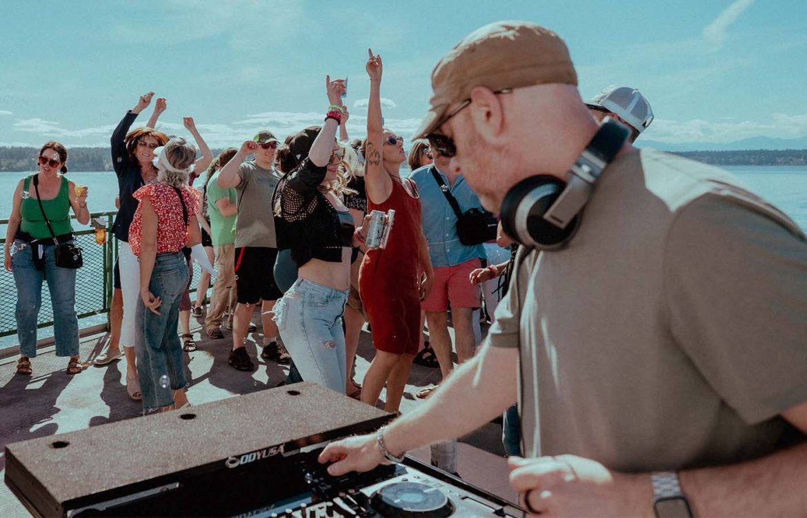An image of a DJ mixing with a large dancing crowd
