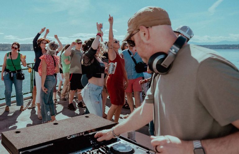 An image of a DJ mixing with a large dancing crowd