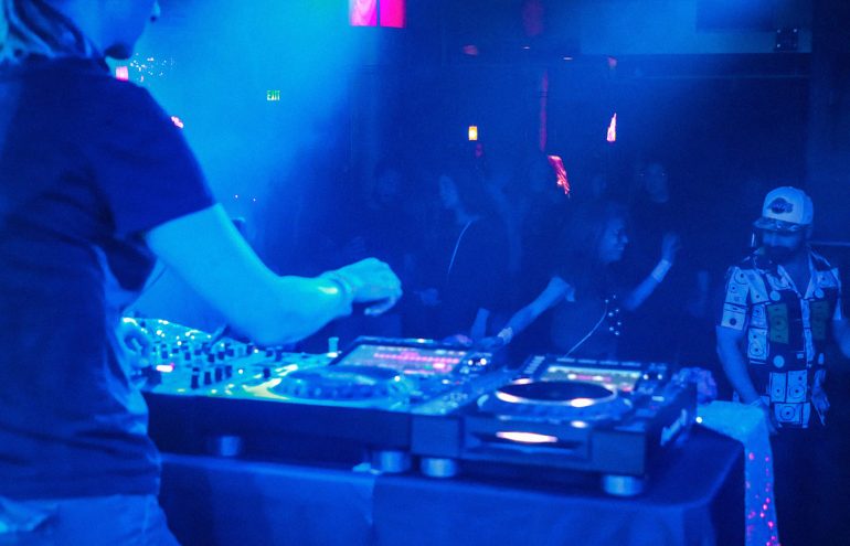 A DJ mixing to a crowd under blue lights